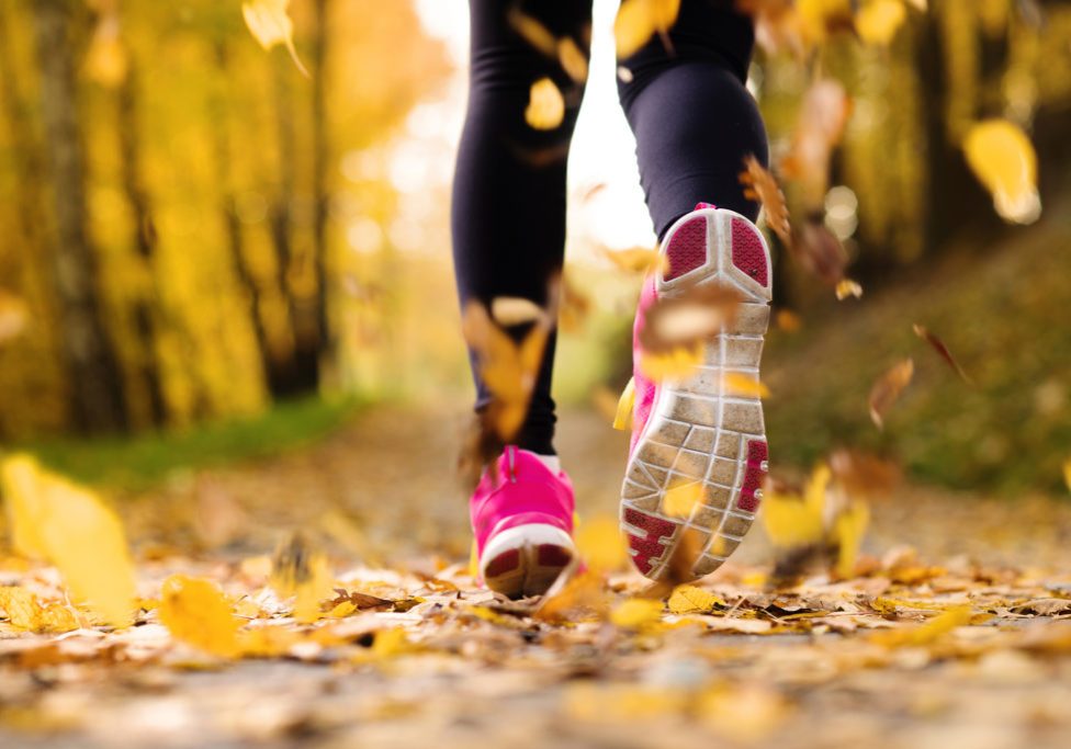 Close up of runner’s feet running in autumn leaves training exercise